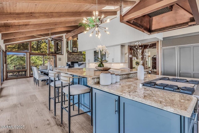 1263 Hidden Woods Dr, Zephyr Cove, NV 89413 - kitchen with custom range hood, light wood-style flooring, a chandelier, blue cabinets, and light stone counters