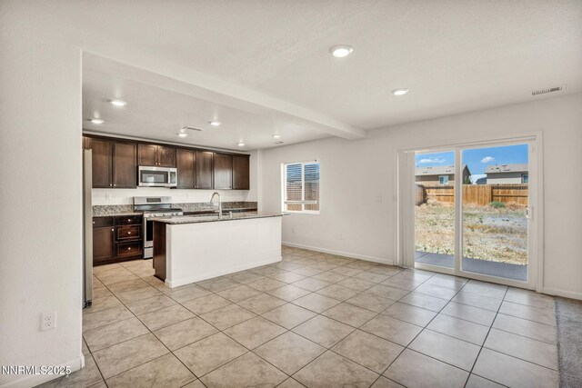 8977 Sagemoor Dr, Reno, NV 89506 - kitchen with stainless steel appliances, recessed lighting, dark brown cabinetry, light tile patterned flooring, and a center island with sink