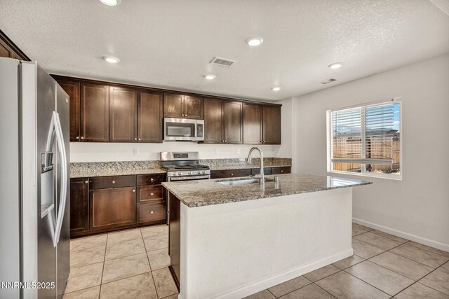 8977 Sagemoor Dr, Reno, NV 89506 - kitchen with stainless steel appliances, dark brown cabinetry, light stone countertops, light tile patterned flooring, and recessed lighting