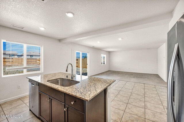 8977 Sagemoor Dr, Reno, NV 89506 - kitchen featuring appliances with stainless steel finishes, dark brown cabinets, healthy amount of natural light, light tile patterned flooring, and a textured ceiling