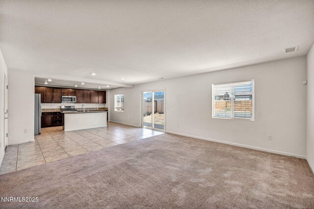 8977 Sagemoor Dr, Reno, NV 89506 - unfurnished living room featuring light carpet, healthy amount of natural light, recessed lighting, light tile patterned floors, and a textured ceiling