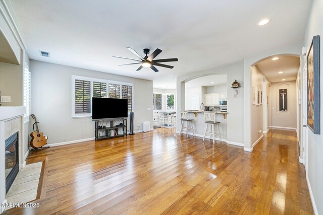 1575 Canyonlands Ct, Reno, NV 89521 - living area featuring a ceiling fan, a fireplace, light wood finished floors, arched walkways, and recessed lighting