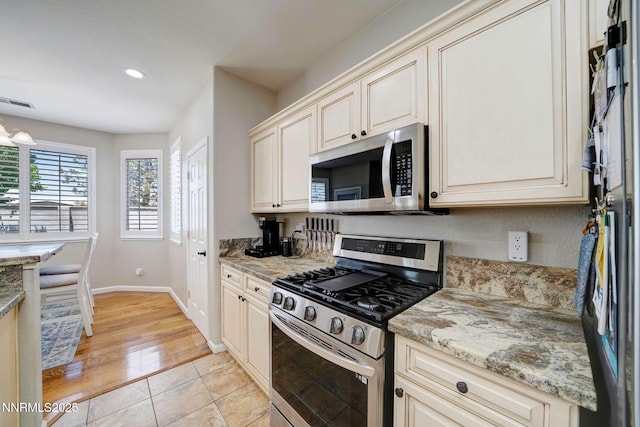 1575 Canyonlands Ct, Reno, NV 89521 - kitchen with appliances with stainless steel finishes, cream cabinetry, recessed lighting, light stone countertops, and light tile patterned flooring