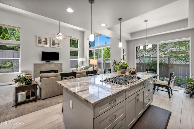 6161 Wycliffe Cir, Reno, NV 89519 - kitchen featuring stainless steel gas stovetop, gray cabinets, a ceiling fan, a fireplace, and light stone countertops