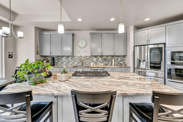 6161 Wycliffe Cir, Reno, NV 89519 - kitchen with appliances with stainless steel finishes, gray cabinets, tasteful backsplash, light stone countertops, and a breakfast bar area