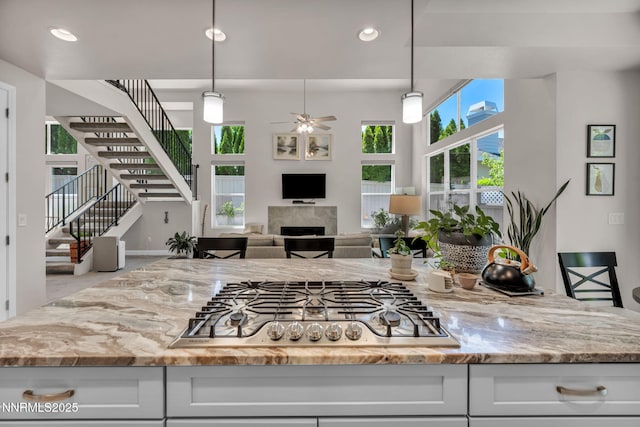 6161 Wycliffe Cir, Reno, NV 89519 - kitchen with stainless steel gas cooktop, ceiling fan, light stone countertops, a fireplace, and white cabinetry