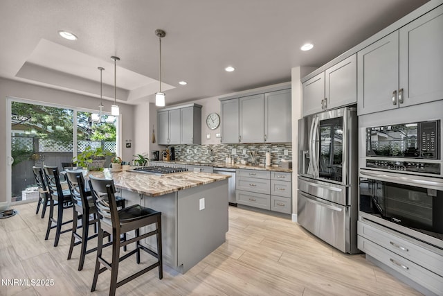 6161 Wycliffe Cir, Reno, NV 89519 - kitchen featuring stainless steel appliances, gray cabinets, light stone countertops, decorative backsplash, and a kitchen breakfast bar