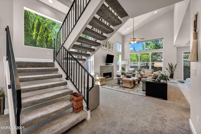 6161 Wycliffe Cir, Reno, NV 89519 - staircase with ceiling fan, a tile fireplace, recessed lighting, carpet flooring, and a towering ceiling