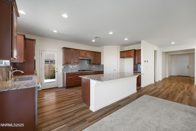 14144 American Pillar Ct, Reno, NV 89511 - kitchen featuring stainless steel gas stovetop, tasteful backsplash, dark wood finished floors, light stone counters, and under cabinet range hood