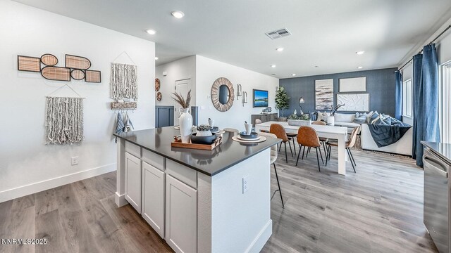 7602 Apex Pl # 106, Reno, NV 89506 - kitchen with dark countertops, a center island, light wood finished floors, recessed lighting, and white cabinetry