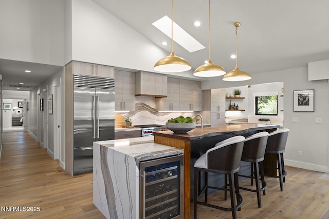 10594 Dixon Ln, Reno, NV 89511 - kitchen with built in refrigerator, a center island with sink, high vaulted ceiling, backsplash, and modern cabinets