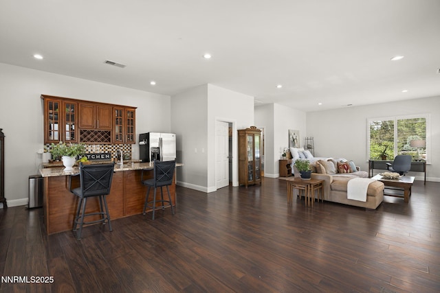 10594 Dixon Ln, Reno, NV 89511 - kitchen with stainless steel fridge with ice dispenser, a kitchen bar, open floor plan, dark wood-type flooring, and recessed lighting