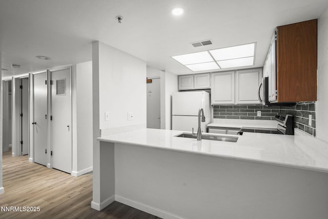 3095 Lakeside Unit 203, Reno, NV 89509 - kitchen with range, stainless steel microwave, a peninsula, light wood finished floors, and tasteful backsplash