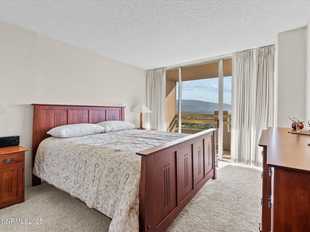 100 N Arlington Ave Unit 20J, Reno, NV 89501 - bedroom featuring light colored carpet, a textured ceiling, a wall of windows, and a mountain view