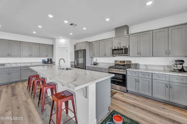 1250 Hubble Ln, Carson City, NV 89705 - kitchen featuring appliances with stainless steel finishes, gray cabinetry, a kitchen breakfast bar, recessed lighting, and light stone countertops