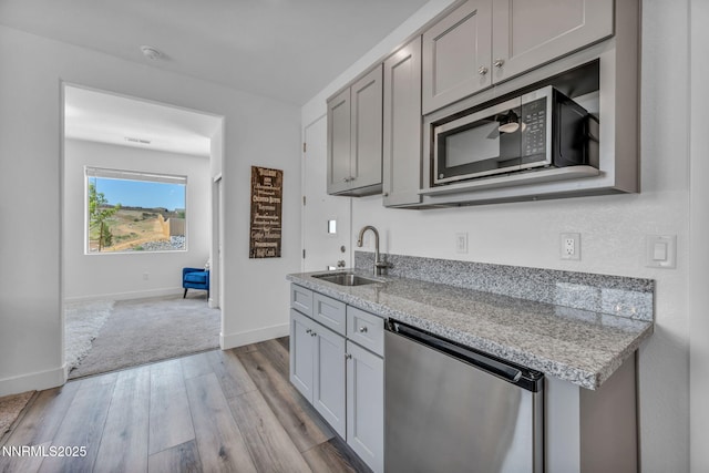 1250 Hubble Ln, Carson City, NV 89705 - kitchen with dishwasher, stainless steel microwave, light wood-type flooring, gray cabinets, and light stone countertops
