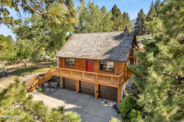 187 Jeannie Ln, Gardnerville, NV 89460 - view of front of home with stairs, concrete driveway, a garage, a chimney, and view of wooded area