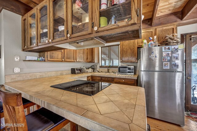 187 Jeannie Ln, Gardnerville, NV 89460 - kitchen featuring appliances with stainless steel finishes, tile counters, light wood finished floors, brown cabinets, and glass insert cabinets