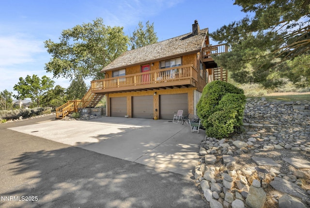 187 Jeannie Ln, Gardnerville, NV 89460 - view of front of house featuring stairway, a chimney, concrete driveway, a garage, and a balcony