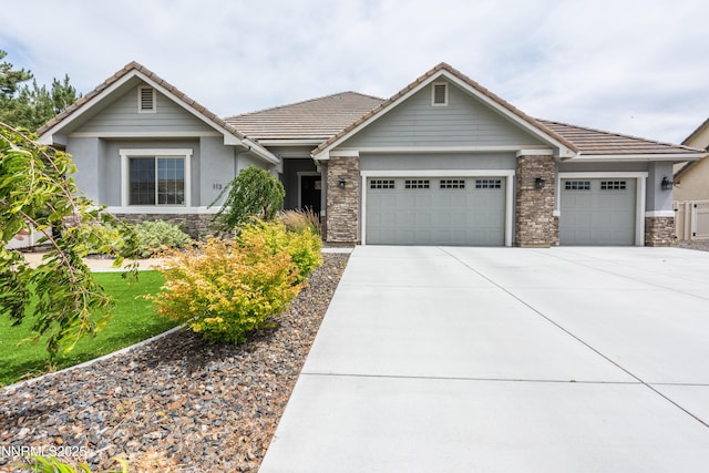 113 Denio Dr, Dayton, NV 89403 - view of front facade featuring an attached garage, stone siding, driveway, stucco siding, and a tile roof