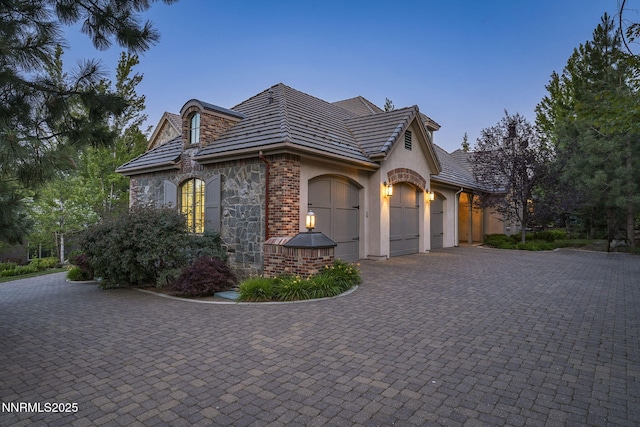 5830 Strasbourg Ct, Reno, NV 89511 - view of side of home featuring an attached garage, decorative driveway, stucco siding, and stone siding