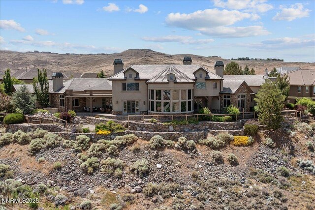 2550 Old Waverly Ct, Sparks, NV 89436 - back of house featuring a chimney, stucco siding, a mountain view, and stone siding