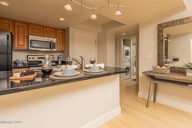450 N Arlington Ave Unit 715, Reno, NV 89503 - kitchen with stainless steel microwave, electric stove, stacked washer / dryer, dark countertops, and freestanding refrigerator
