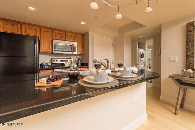 450 N Arlington Ave Unit 715, Reno, NV 89503 - kitchen featuring appliances with stainless steel finishes, stacked washer / dryer, brown cabinetry, dark countertops, and recessed lighting