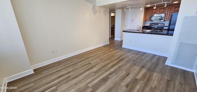 450 N Arlington Ave Unit 715, Reno, NV 89503 - kitchen featuring stainless steel appliances, track lighting, dark countertops, wood finished floors, and brown cabinets