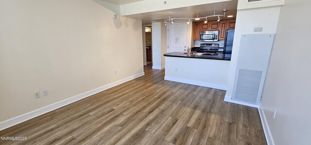 450 N Arlington Ave Unit 715, Reno, NV 89503 - kitchen featuring stainless steel appliances, wood finished floors, track lighting, dark countertops, and brown cabinets