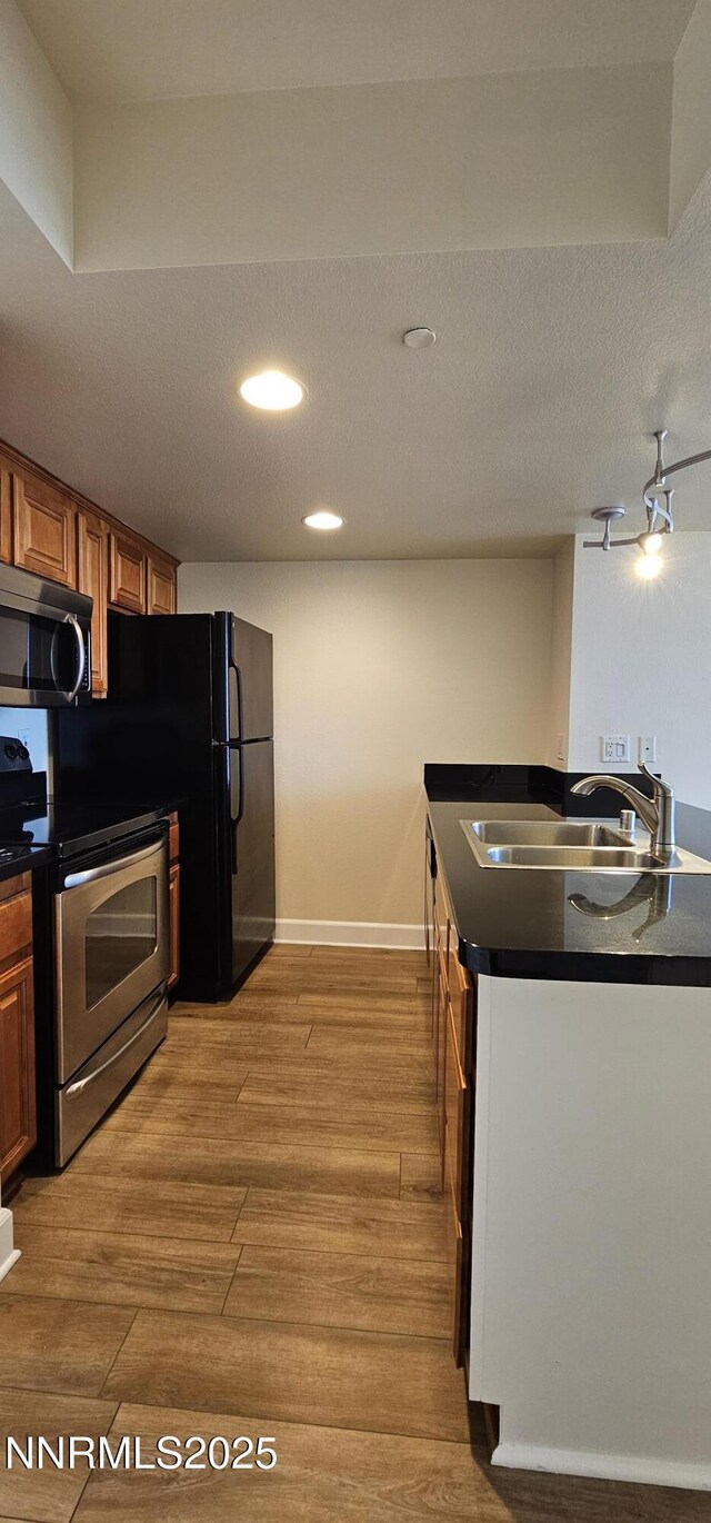 450 N Arlington Ave Unit 715, Reno, NV 89503 - kitchen with stainless steel appliances, dark countertops, light wood-style flooring, recessed lighting, and brown cabinetry