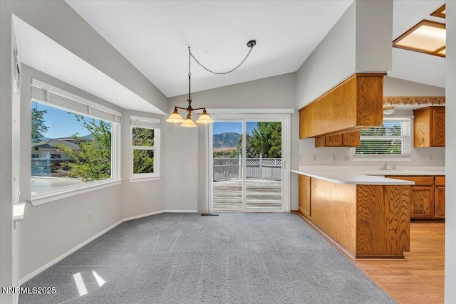 971 Shadow Ln, Carson City, NV 89705 - kitchen with vaulted ceiling, brown cabinetry, healthy amount of natural light, a peninsula, and light countertops