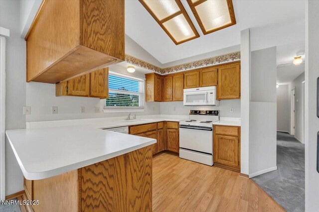 971 Shadow Ln, Carson City, NV 89705 - kitchen with white appliances, a peninsula, light countertops, brown cabinets, and lofted ceiling