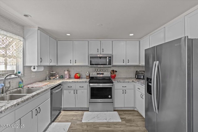 1510 E Slide Mountain Dr, Carson City, NV 89706 - kitchen with stainless steel appliances, white cabinetry, light wood finished floors, tasteful backsplash, and light stone counters