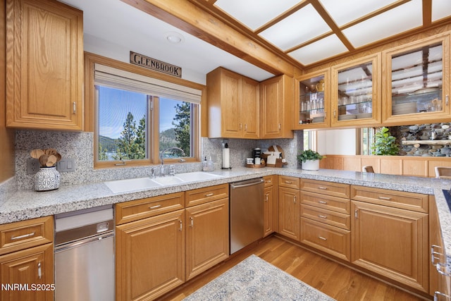 187 Yellow Jacket Rd, Glenbrook, NV 89413 - kitchen with stainless steel dishwasher, light wood-type flooring, tasteful backsplash, glass insert cabinets, and brown cabinetry
