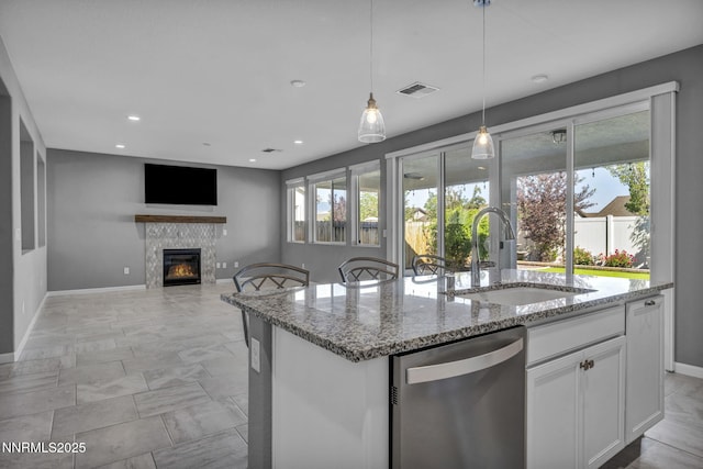 1975 Phaethon Ln, Reno, NV 89521 - kitchen featuring dishwasher, light stone counters, a center island with sink, white cabinetry, and decorative light fixtures
