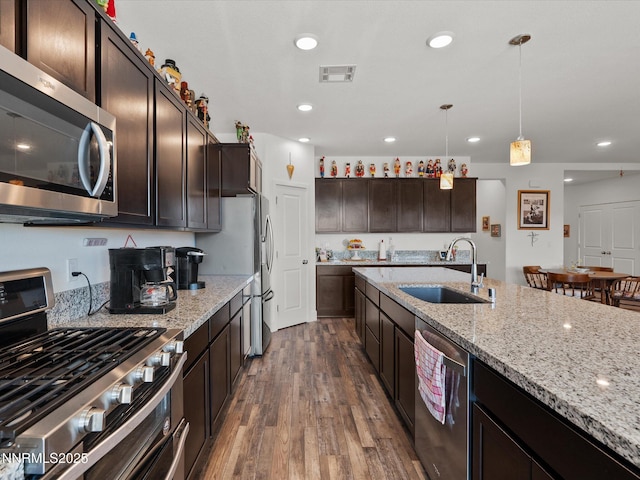 2217 Millville Dr, Spanish Springs, NV 89441 - kitchen with appliances with stainless steel finishes, dark wood finished floors, light stone counters, dark brown cabinets, and decorative light fixtures