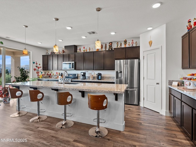 2217 Millville Dr, Spanish Springs, NV 89441 - kitchen with stainless steel appliances, dark brown cabinetry, dark wood-style floors, recessed lighting, and decorative light fixtures