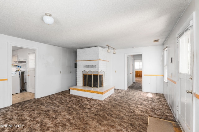 5385 Carol Dr, Sun Valley, NV 89433 - unfurnished living room with washer / dryer, a textured ceiling, carpet, a fireplace, and a wainscoted wall