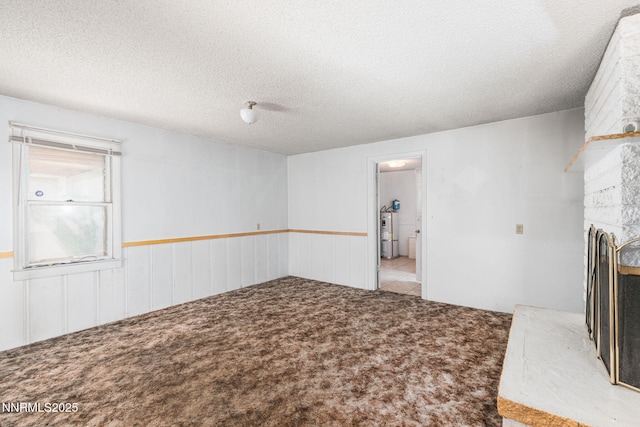 5385 Carol Dr, Sun Valley, NV 89433 - unfurnished living room featuring carpet flooring, wainscoting, a large fireplace, strapped water heater, and a textured ceiling