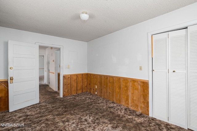 5385 Carol Dr, Sun Valley, NV 89433 - unfurnished bedroom with wainscoting, carpet flooring, wood walls, a textured ceiling, and a closet