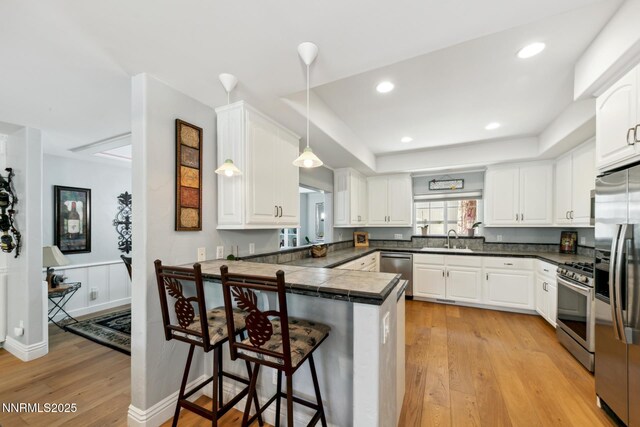 1064 Lucerne Way, Incline Village, NV 89451 - kitchen with appliances with stainless steel finishes, a peninsula, light wood-style flooring, a breakfast bar area, and white cabinetry