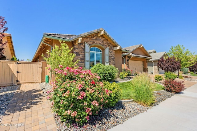 2021 Neviekay Ln, Reno, NV 89521 - ranch-style home with stone siding, an attached garage, a gate, a tile roof, and driveway