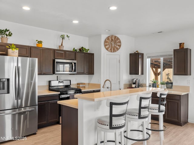 1332 Serenity Cir, Fernley, NV 89408 - kitchen featuring appliances with stainless steel finishes, light countertops, dark brown cabinets, light wood-style flooring, and recessed lighting