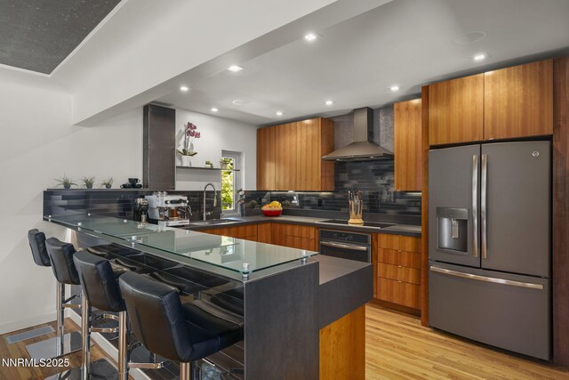 1296 Nixon Ave, Reno, NV 89509 - kitchen featuring appliances with stainless steel finishes, wall chimney exhaust hood, a kitchen bar, brown cabinets, and recessed lighting