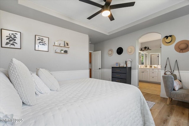 7470 Windswept Loop, Sparks, NV 89436 - bedroom with light wood finished floors, ensuite bath, wainscoting, a tray ceiling, and arched walkways