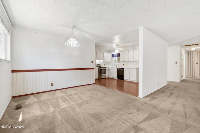 2960 Santa Ana Dr, Reno, NV 89502 - unfurnished living room featuring light colored carpet, ceiling fan, a wainscoted wall, and a textured ceiling