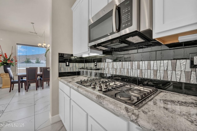 11575 Anthem Dr, Spanish Springs, NV 89441 - kitchen with stainless steel appliances, light marble finish floors, a chandelier, tasteful backsplash, and white cabinets
