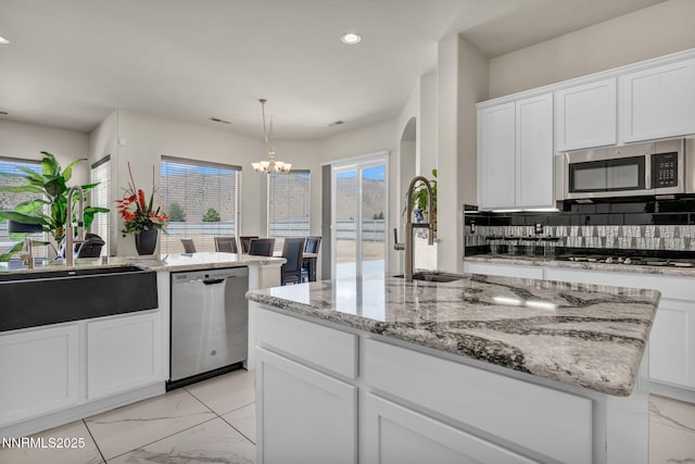 11575 Anthem Dr, Spanish Springs, NV 89441 - kitchen featuring appliances with stainless steel finishes, light marble finish flooring, tasteful backsplash, a chandelier, and white cabinets