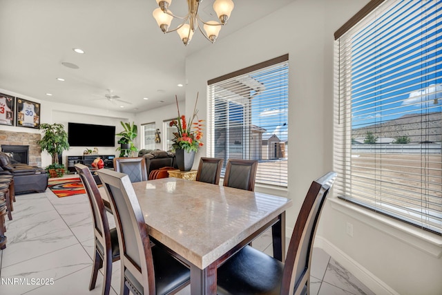 11575 Anthem Dr, Spanish Springs, NV 89441 - dining room featuring light marble finish flooring, a glass covered fireplace, a chandelier, recessed lighting, and a ceiling fan